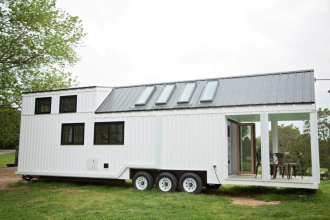 white tiny home on wheels on grassy area