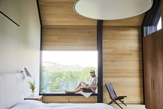 person reading a book while sitting in large window seat