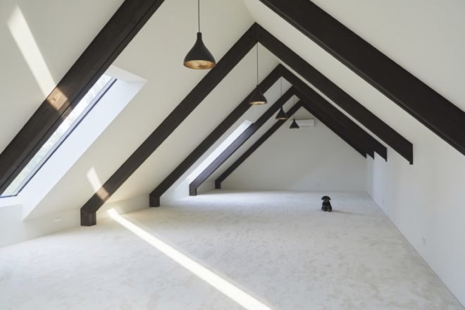 attic with white walls and floors and exposed wood ceiling beams