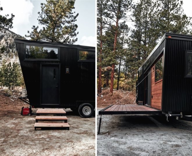 black RV with stairs leading to door and a wood deck