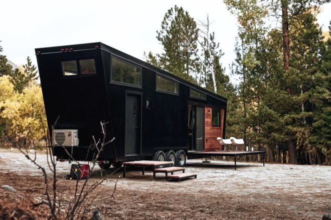 angled view of black tiny home with wood deck