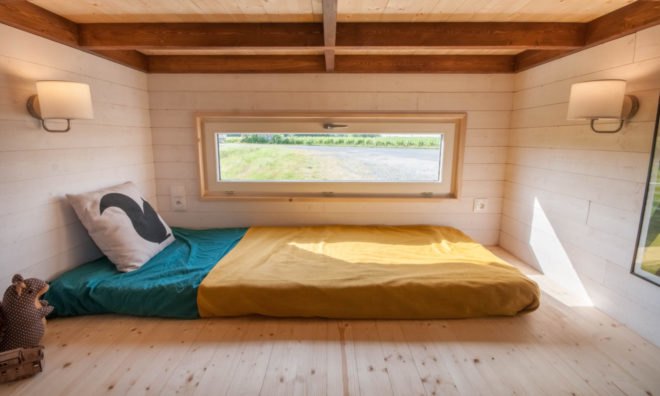 a bed with a yellow blanket and large window