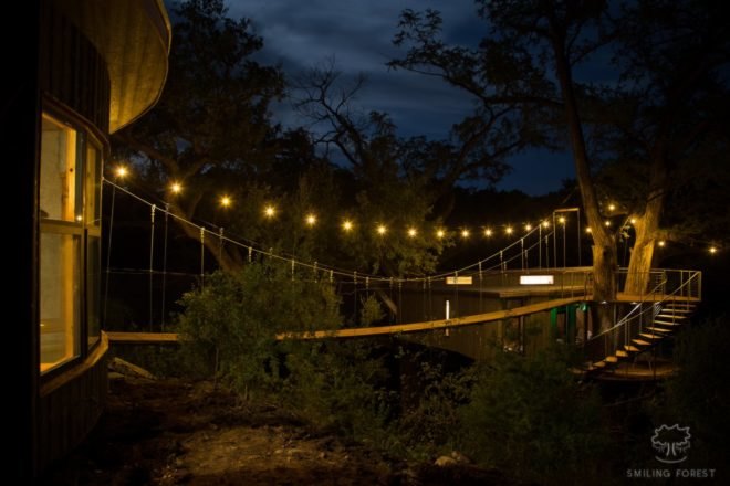 suspension bridge with lights leading to treehouse