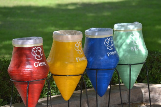 Red, yellow, blue and green recycling bins in a grassy lot