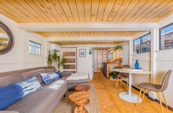 a living room with long sofa and small dining area