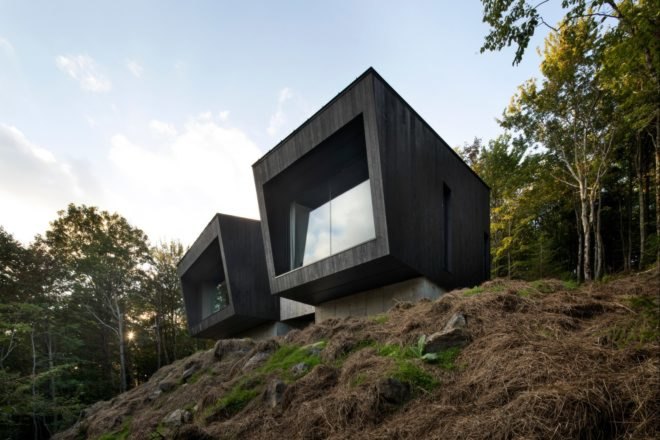 two black cabins with glass facades and slanted roofs