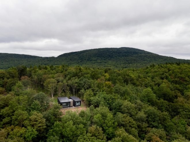 aerial view of two black cabins in a forest