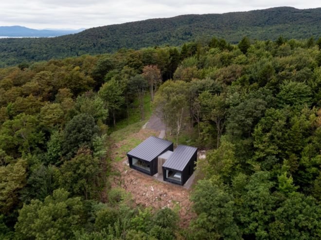 two black cabins surrounded by a forest
