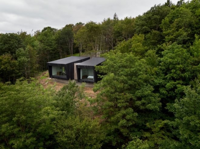 two black cabins surrounded by greenery