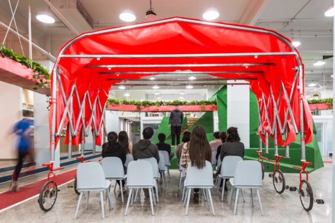 people sitting in white chairs under a red canopy