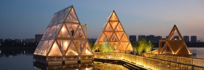 triangular wood structure floating on water and lit up at night