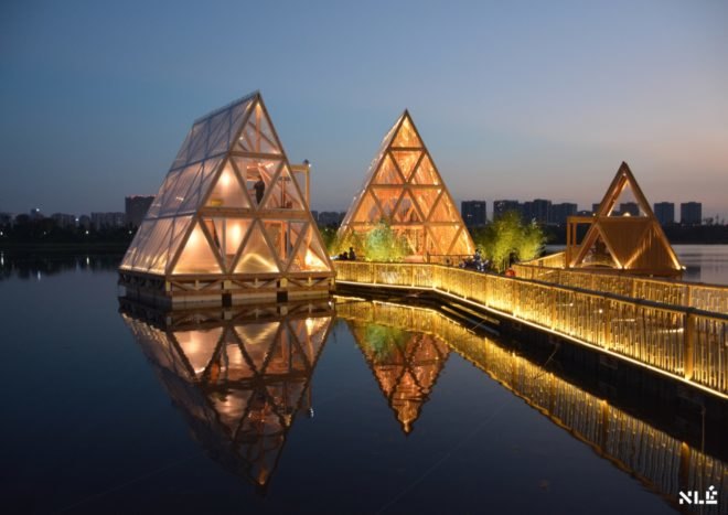 triangular wood structure floating on water and lit up at night