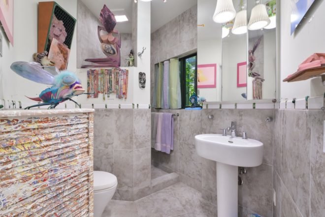 white and gray bathroom filled with colorful art