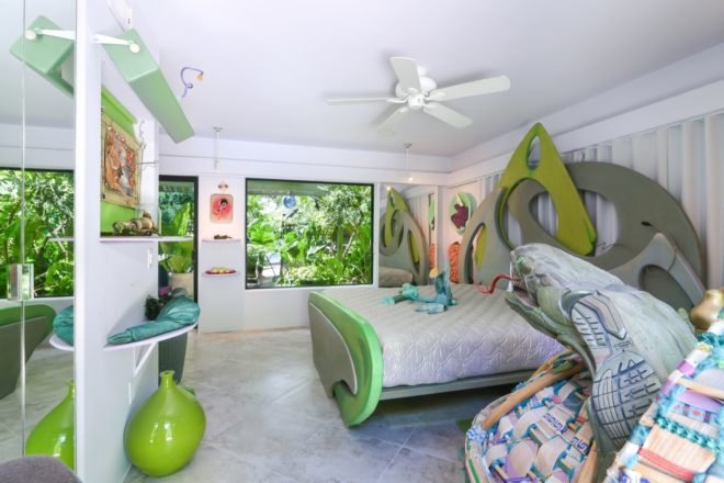 white bedroom with sculptural green bed and green art