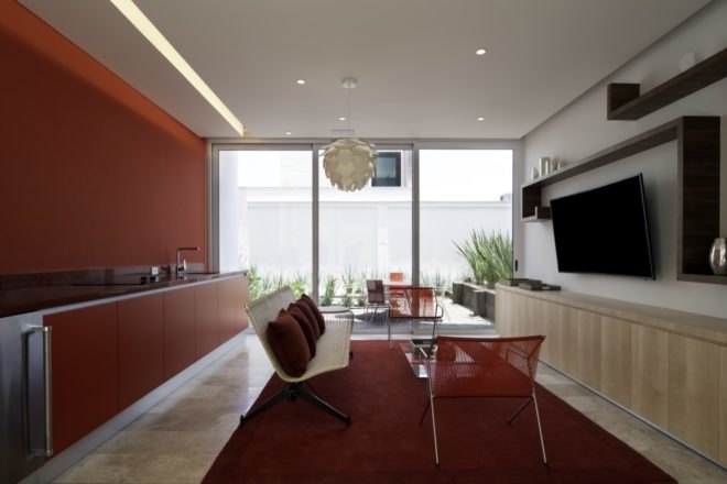 red kitchen with red cabinets and a white bench with red pillows facing a TV