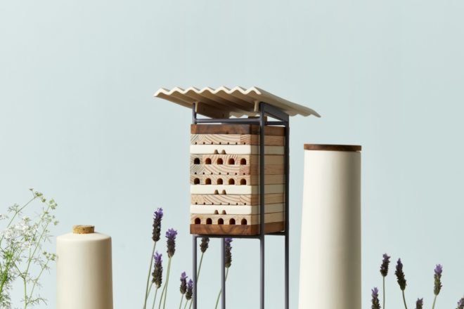 small rectangular wood shelter and two cylindrical white shelters for bees
