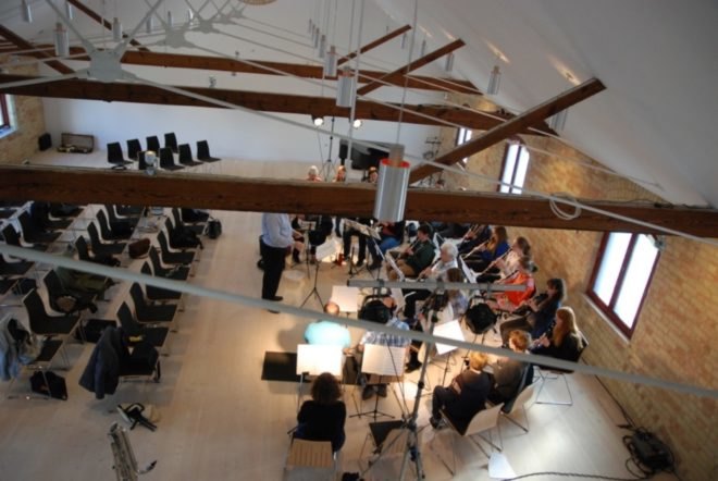 band playing instruments in white room with wood ceiling beams