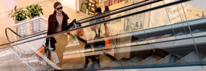 woman with shopping bags on escalator in mall