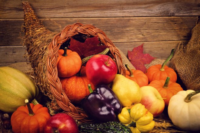 cornucopia filled with fruits and vegetables on wood table