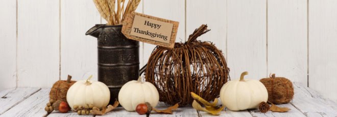 pumpkins, tin container of wheat, twig pumpkin and leaves on a white table