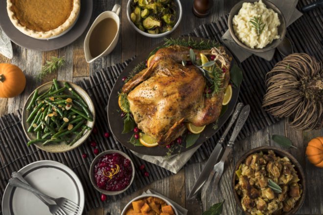 turkey, green beans, mashed potatoes, cranberry sauce, gravy, stuffing and pumpkin pie on a table