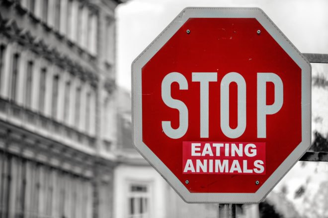 red stop sign with a sticker that says, "Eating Animals" just below the word, "Stop"