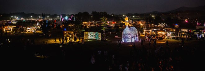 several stages and vendors with colorful lights at night