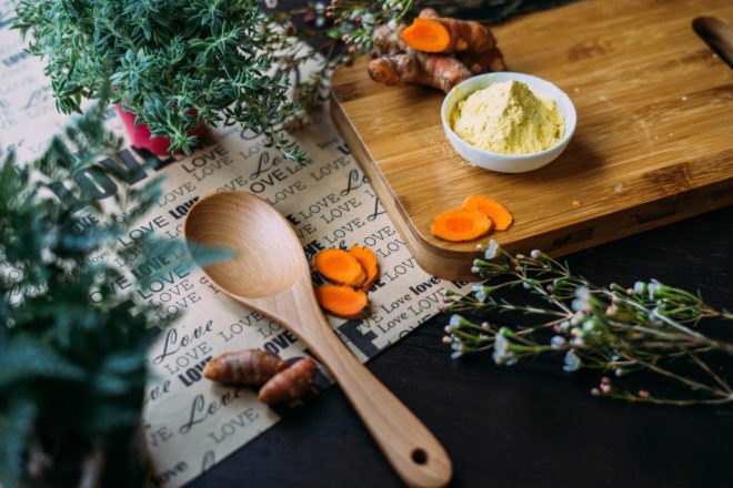 cut ginger on a cutting board near plants and wooden spoon