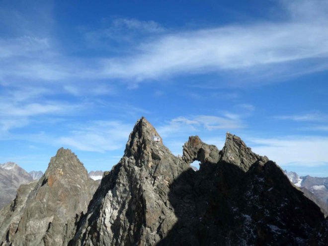 tiny grey shelter on mountain ridge
