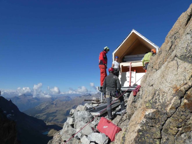 men standing next to tiny shelter with pitched roof
