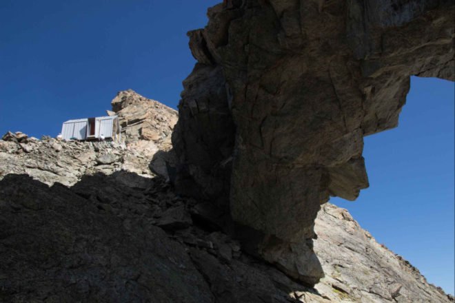 tiny grey shelter on mountain ridge