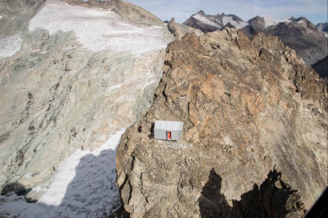 small gray shelter on rocky mountainside