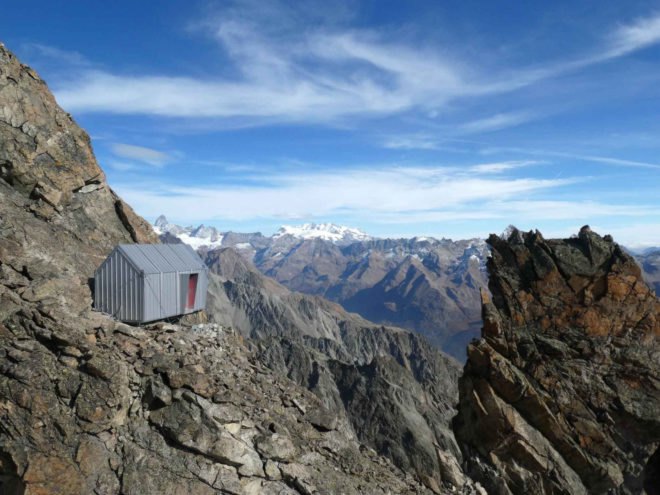 tiny gray shelter on mountain ridge