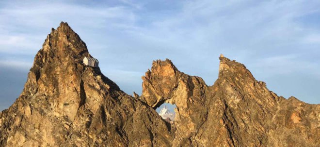 tiny grey shelter on mountain ridge