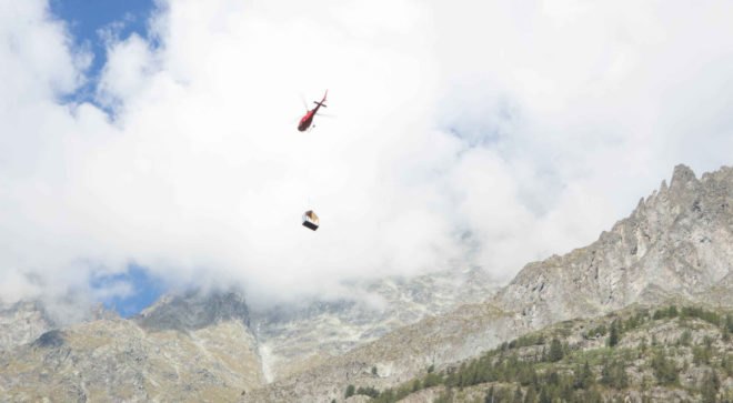 helicopter carrying one piece of tiny gray shelter