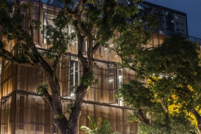 glass building with wooden louvers lit from within at night