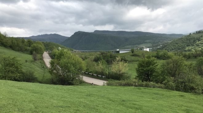 rolling green hills with white building in the distance