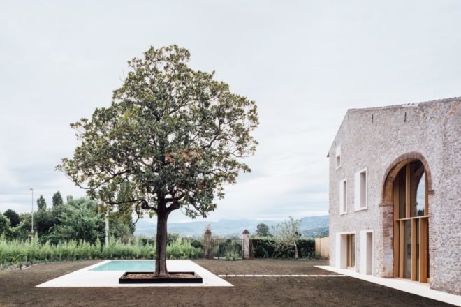 stone farmhouse with large tree beside small pool