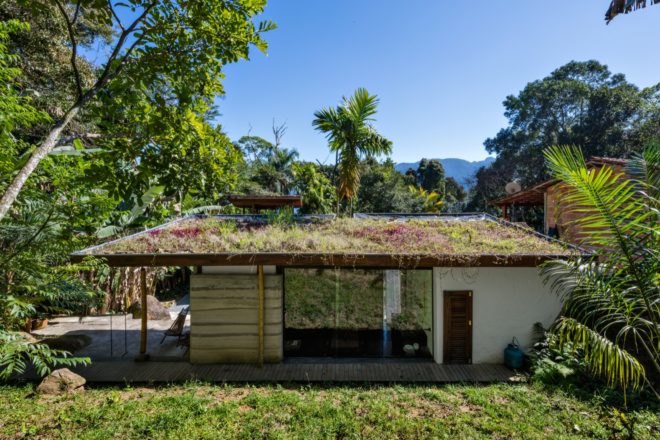small white and bamboo house with green roof