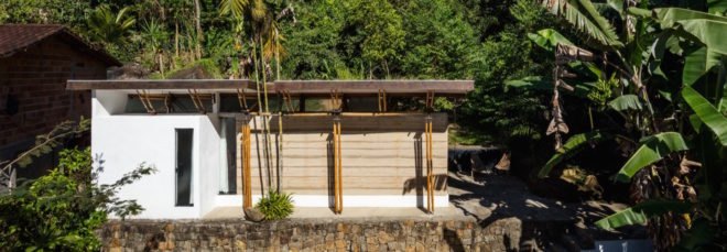 small white and bamboo house with green roof