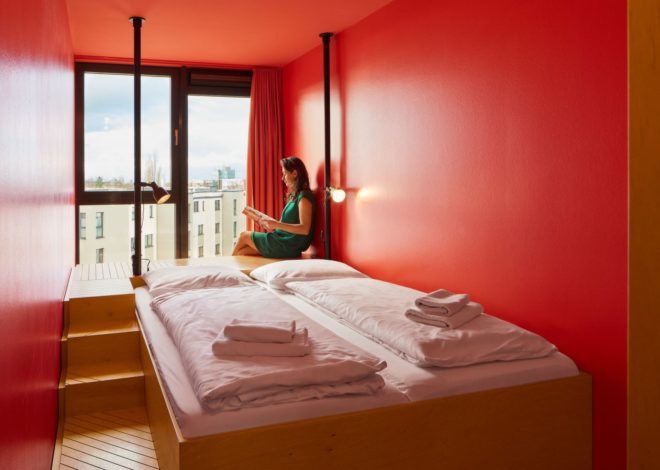 a woman sitting reading a book at the end of a bed.