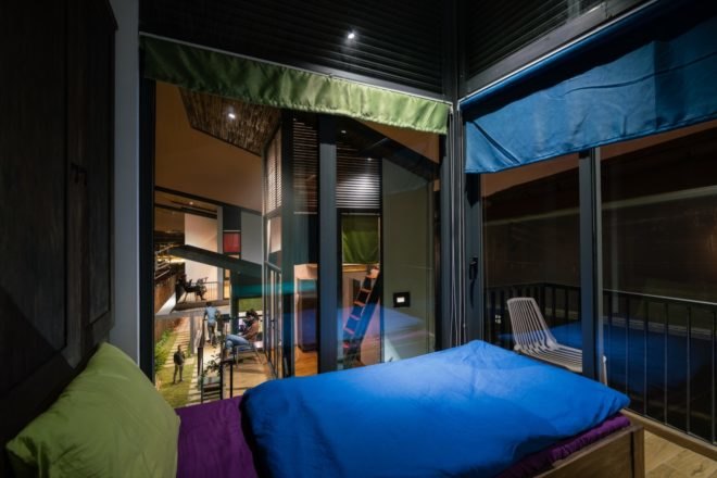 interior of a bedroom at night with windows open showing the close proximity to the other dwellings