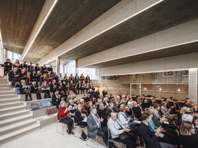 people sitting on benches in a lecture hall