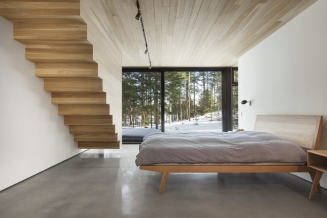 bedroom with large glass windows wood staircase and cement flooring