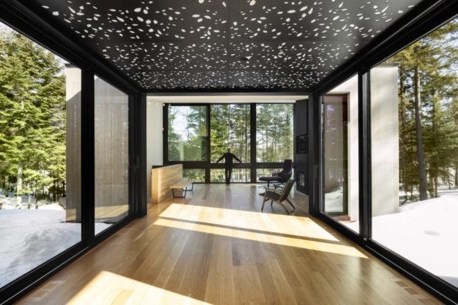 wood floors line the interior of the sunlit home with floor to ceiling windows