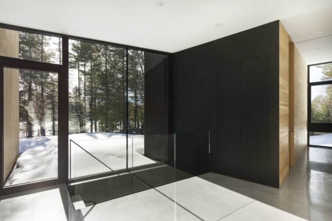 interior of the minimalist home with tile floors and large windows towards the forest