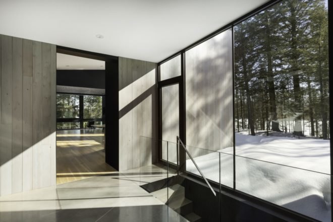 interior of the minimalist home with tile floors and large windows towards the forest