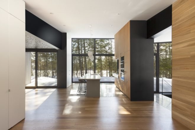 wood floors line the interior of the sunlit home with floor to ceiling windows