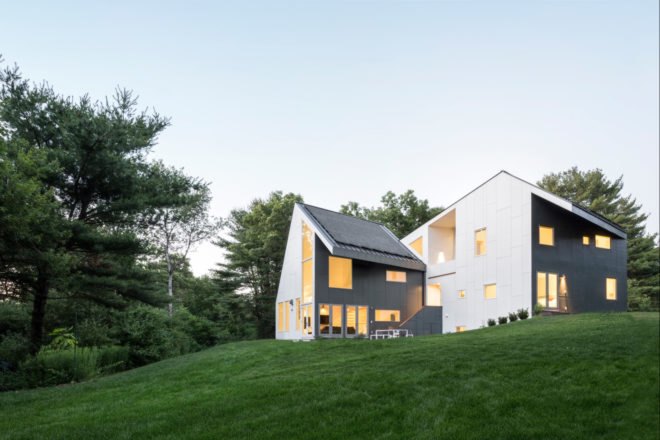 angular white and gray home on a green hill