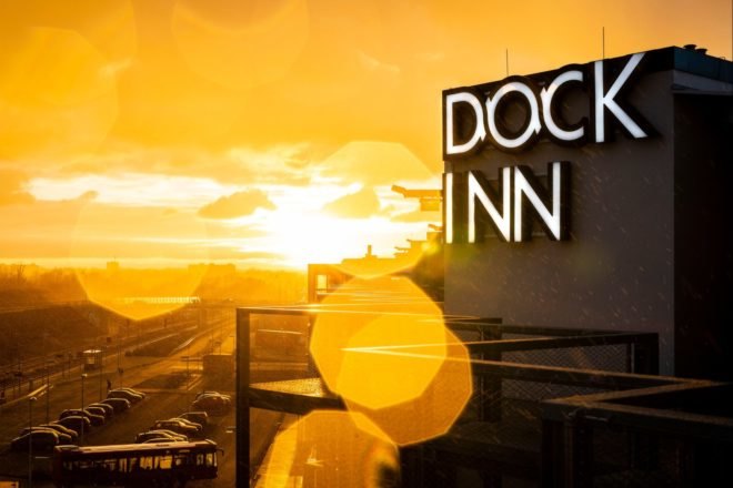a dock inn sign with sunsetting in the background